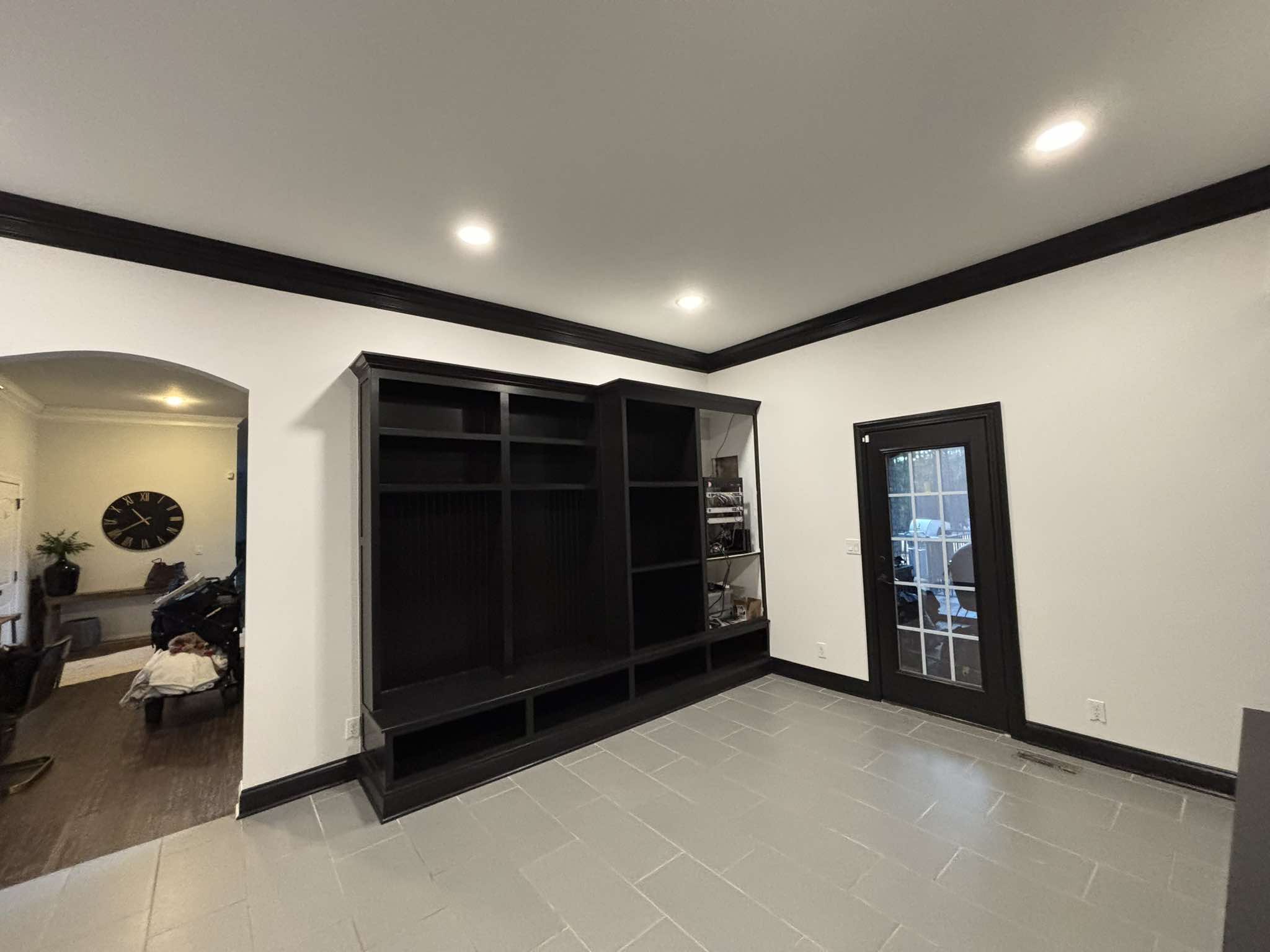 Completed black built-in shelves and coordinated black door and trim viewed across the room