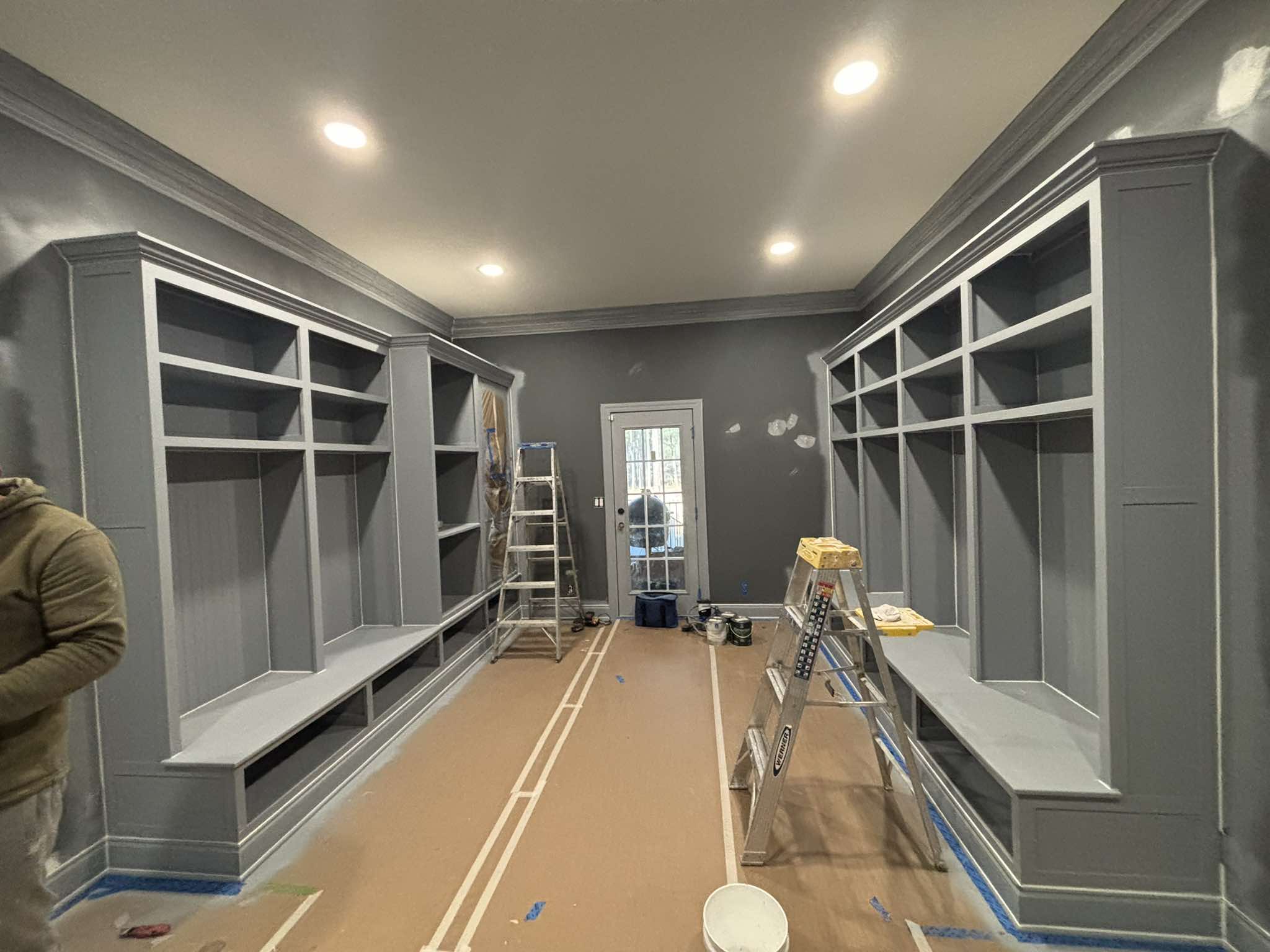 Pair of built-in storage units during painting with gray surfaces and protected flooring