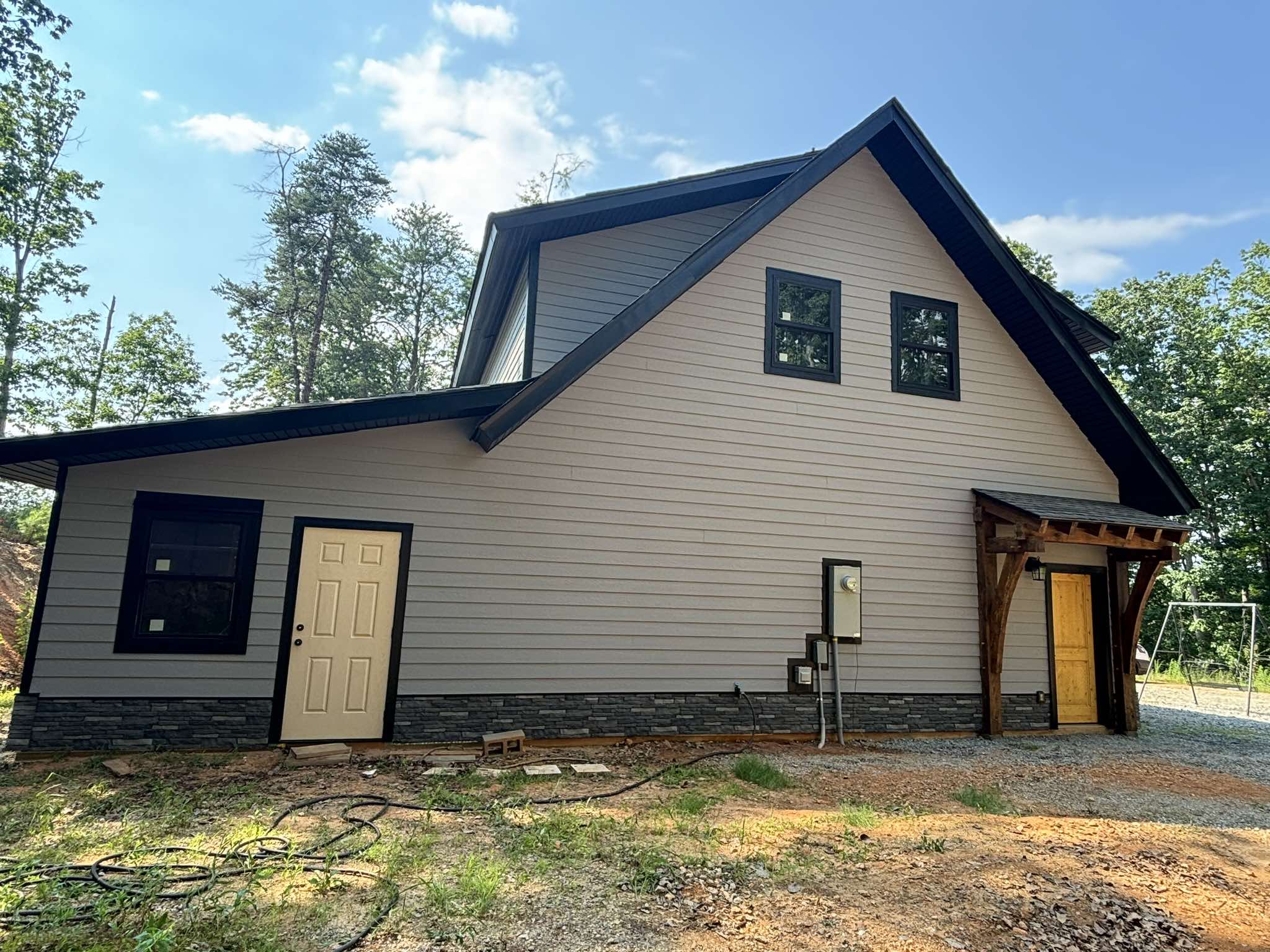 Finished garage side elevation with light gray siding, black trim, and dark doors