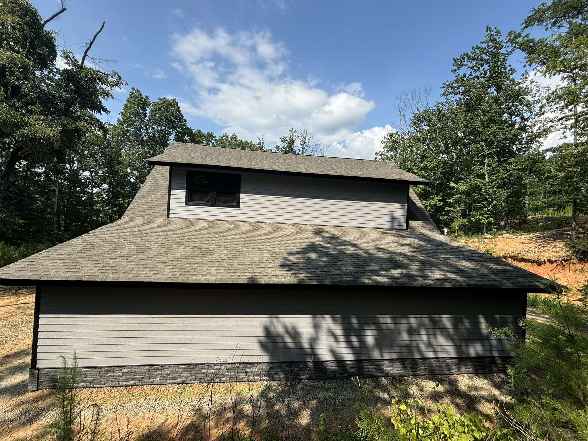 Rear garage elevation before painting with tan siding and dark lower trim