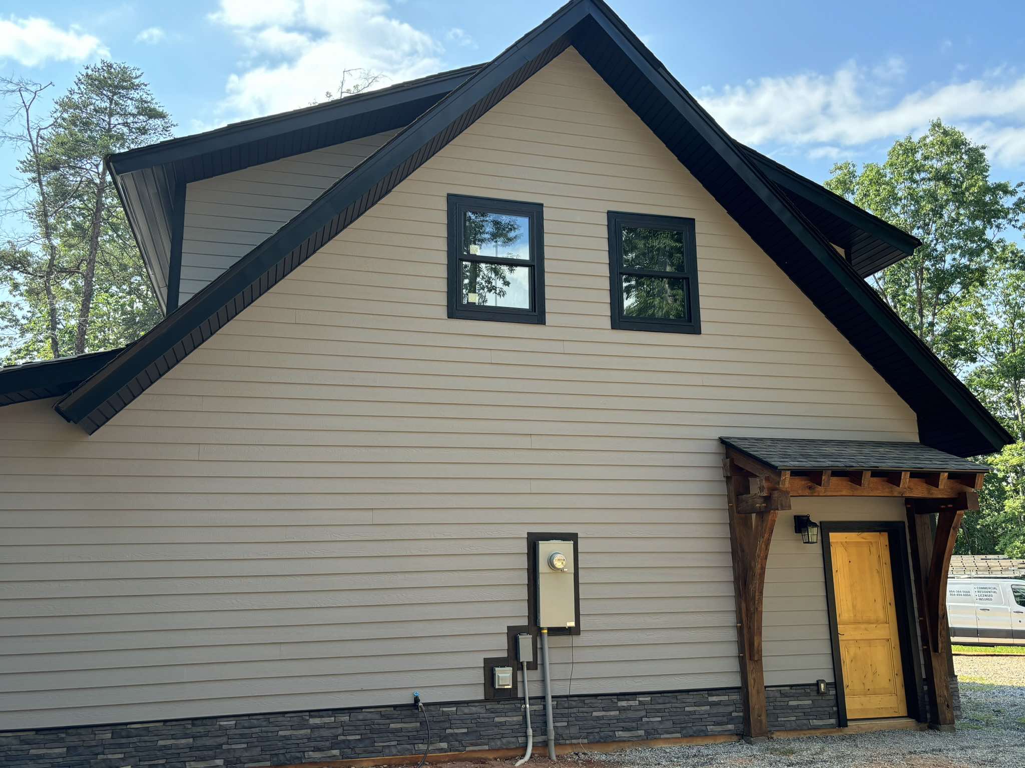 Finished gable end with light gray siding, crisp black fascia, and black window trim