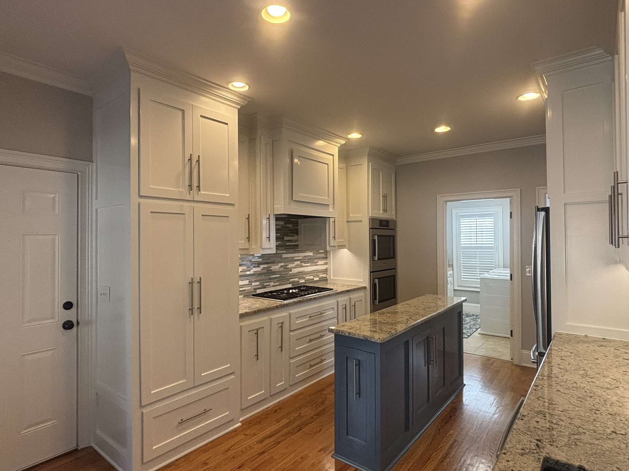 Finished pantry wall with tall white cabinets and a dark center island