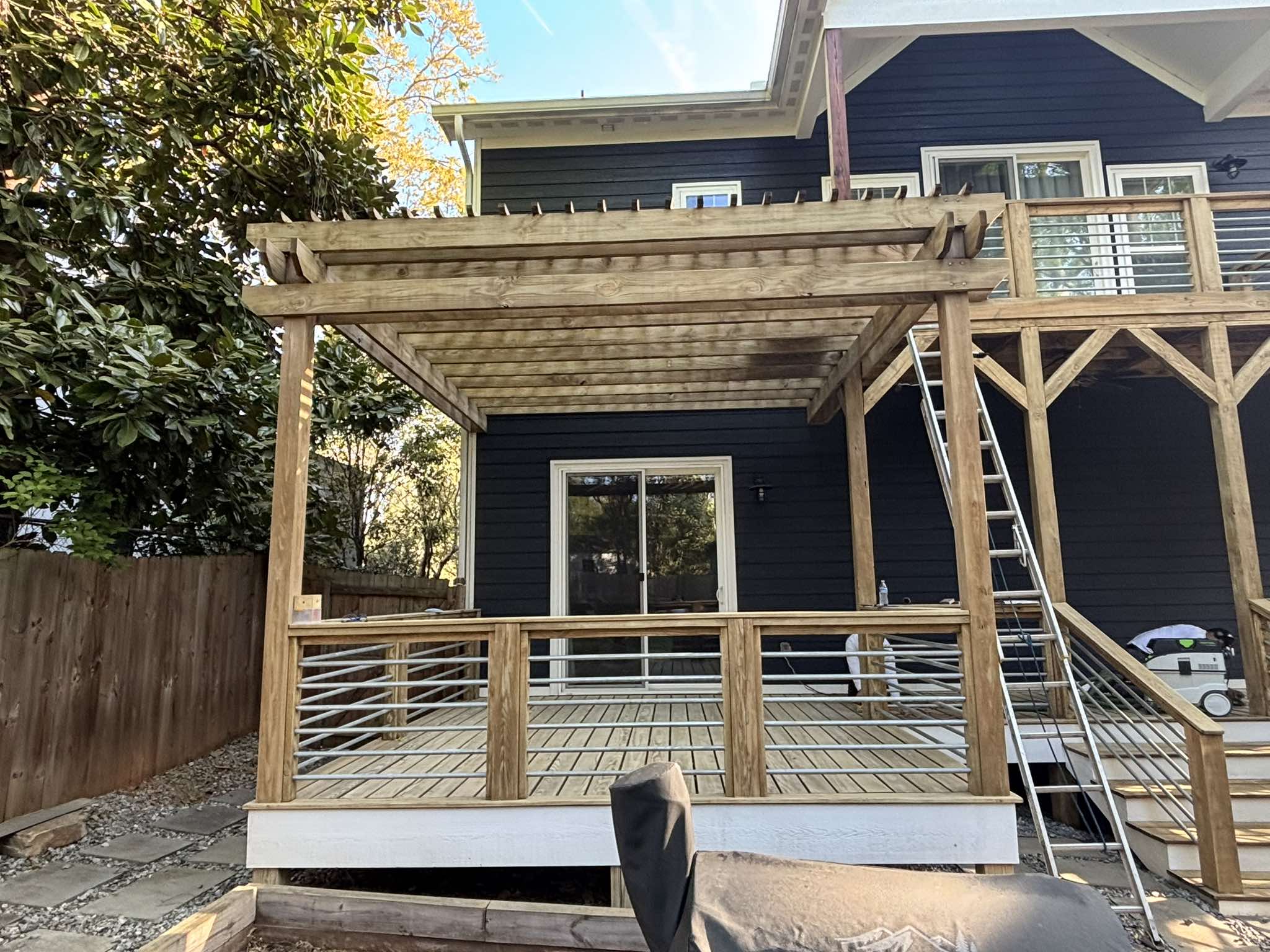 Deck and pergola before staining with bare wood railings, posts, beams, and stairs