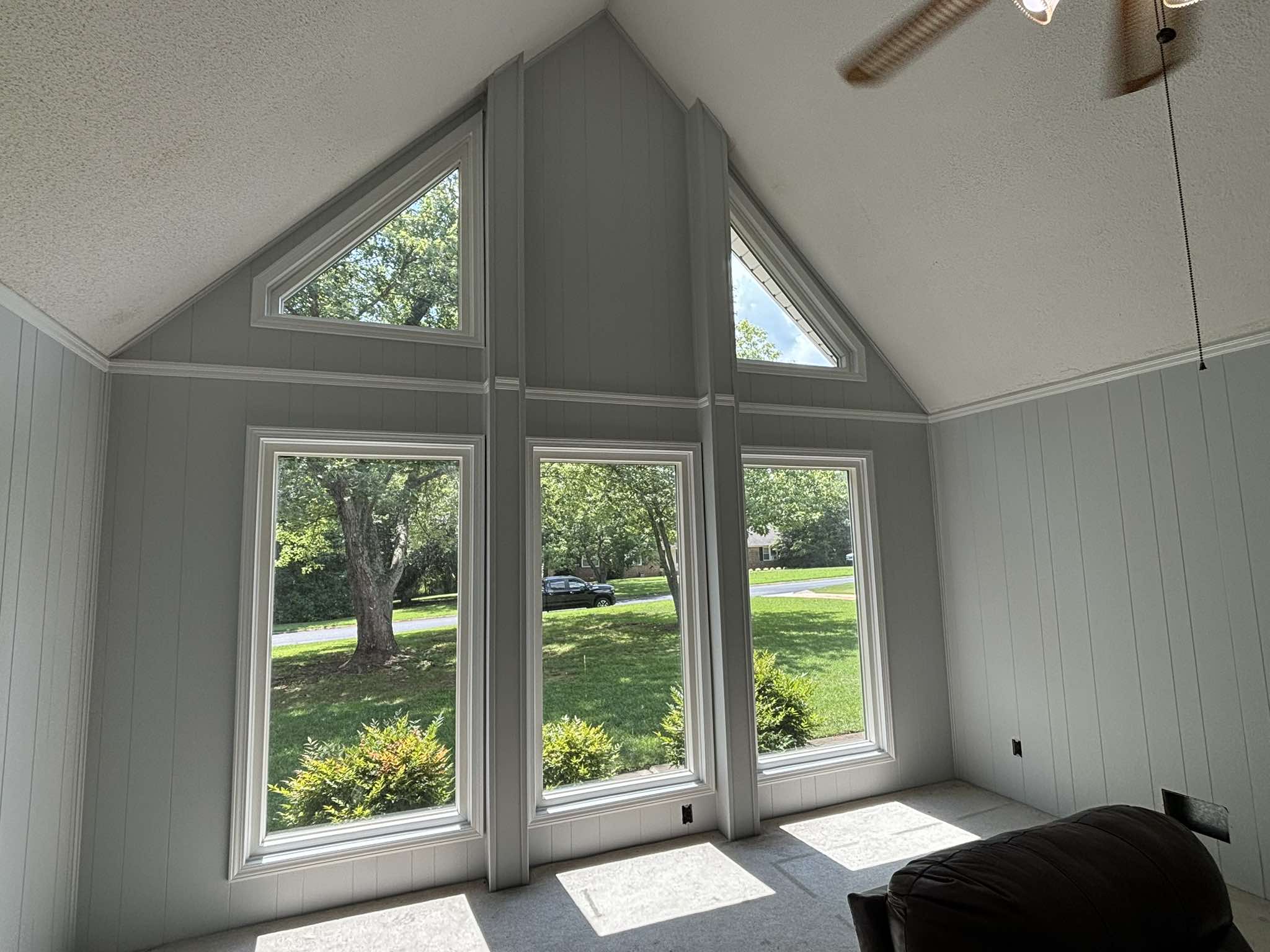 Angled finished view of the tall window wall, pale gray panels, and white architectural lines