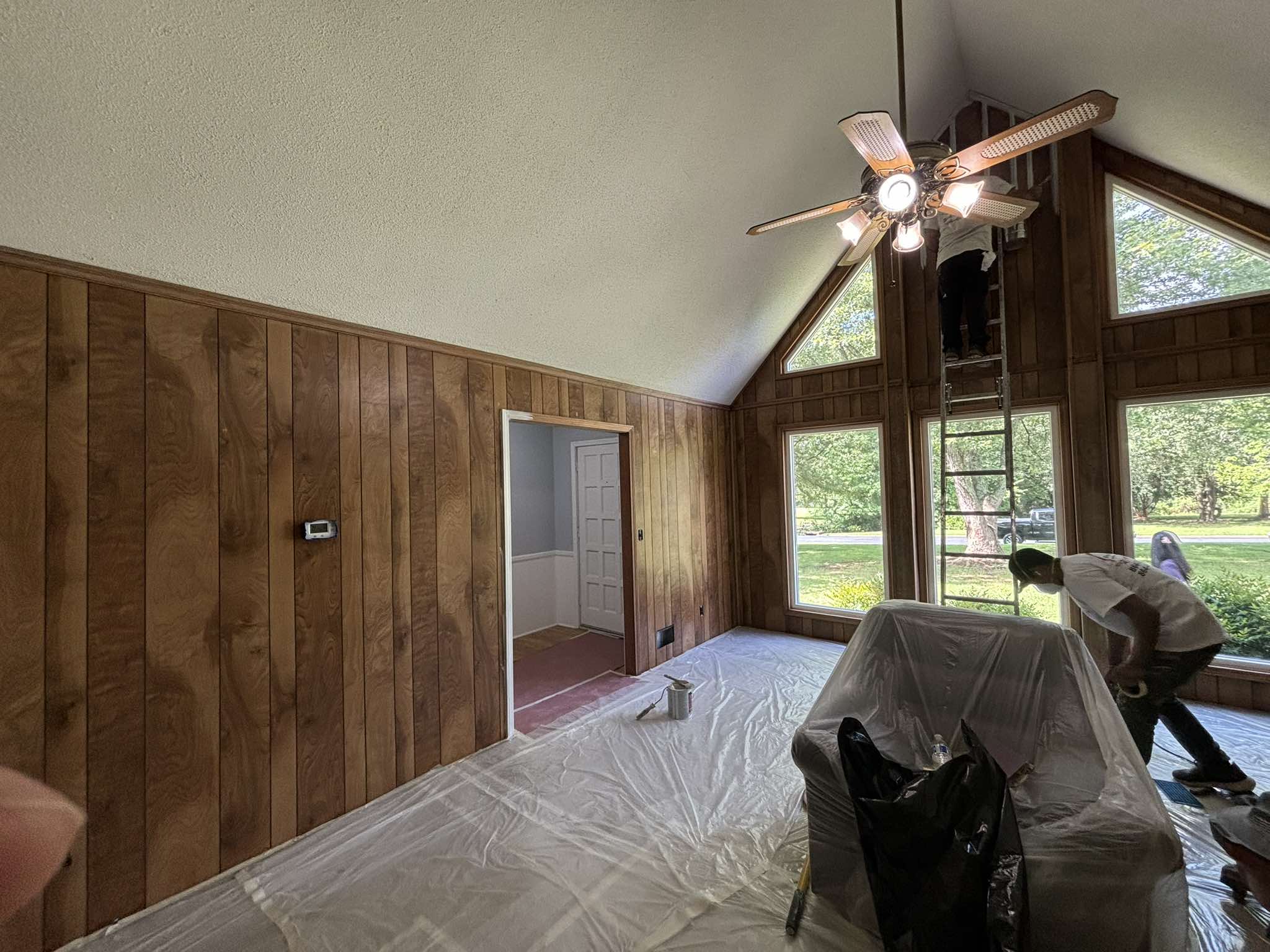 Wood-paneled vaulted room before painting with furniture and floors protected